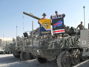 Soldiers standing on a vehicle holding a Buffalo Bills and Buffalo Sabres banner