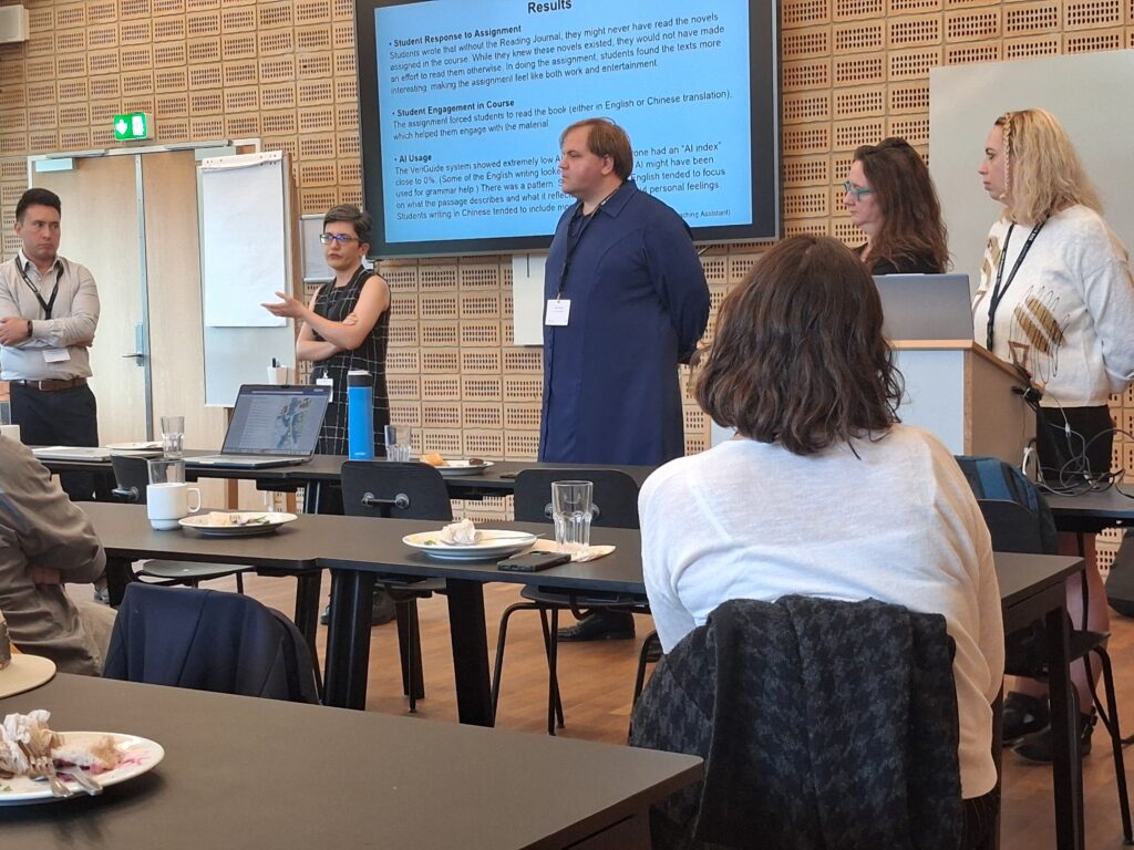 An image of the speakers at the Narrative 2026 conference pedagogy lunch. Cody Mejeur is in the middle of a handful of speakers, standing in a blue robe with their conference badge.