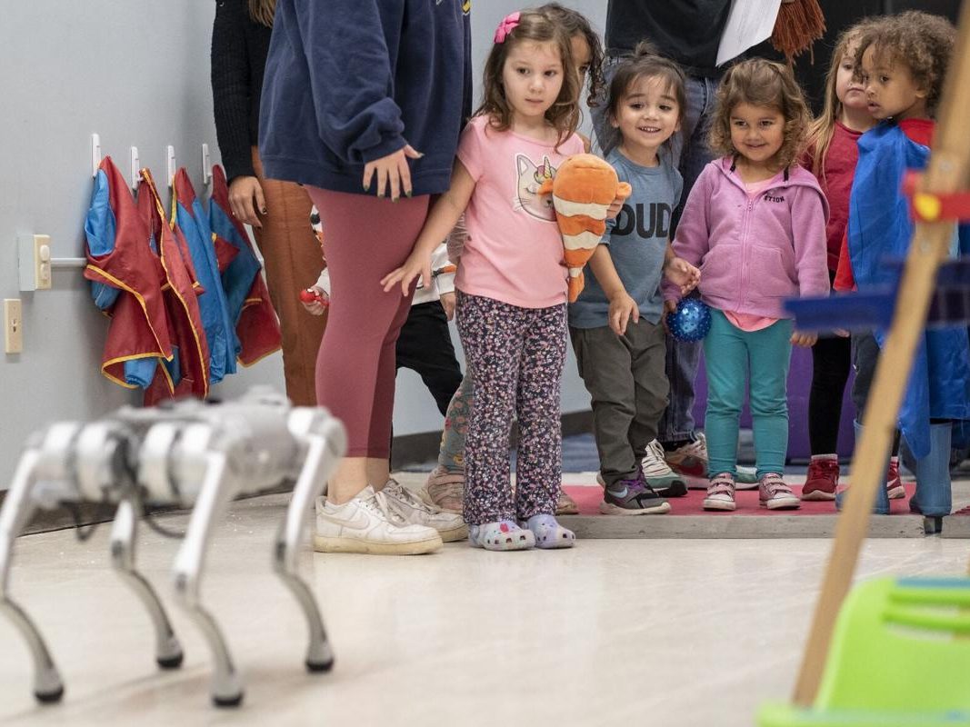 Young students in a group looking at a robot