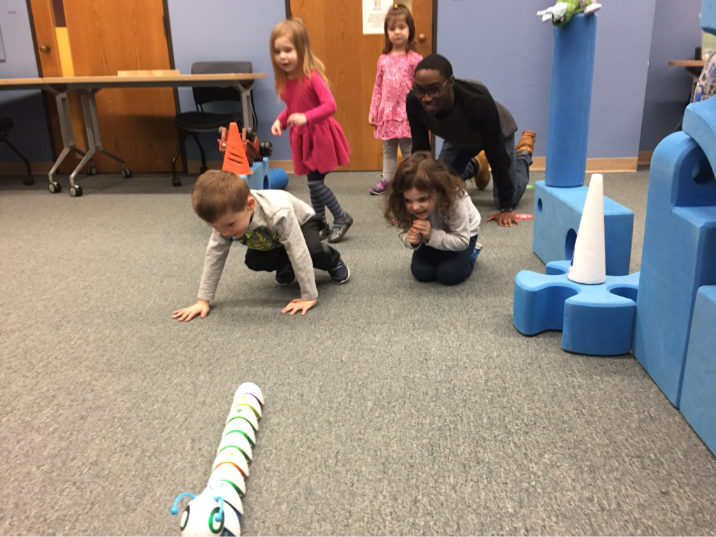 A teacher and young students playing with a robot