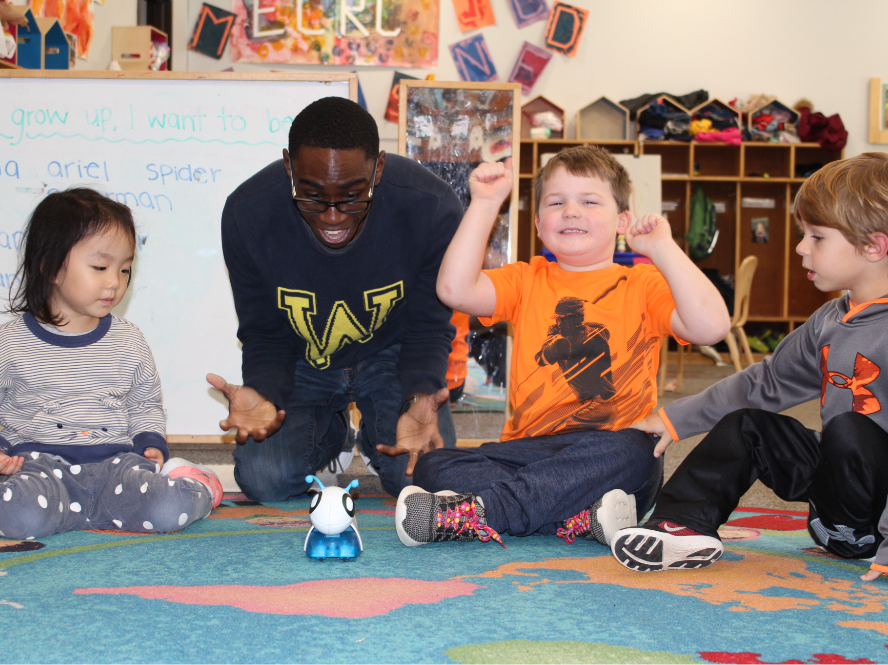 A teacher and three young children playing with a robot toy