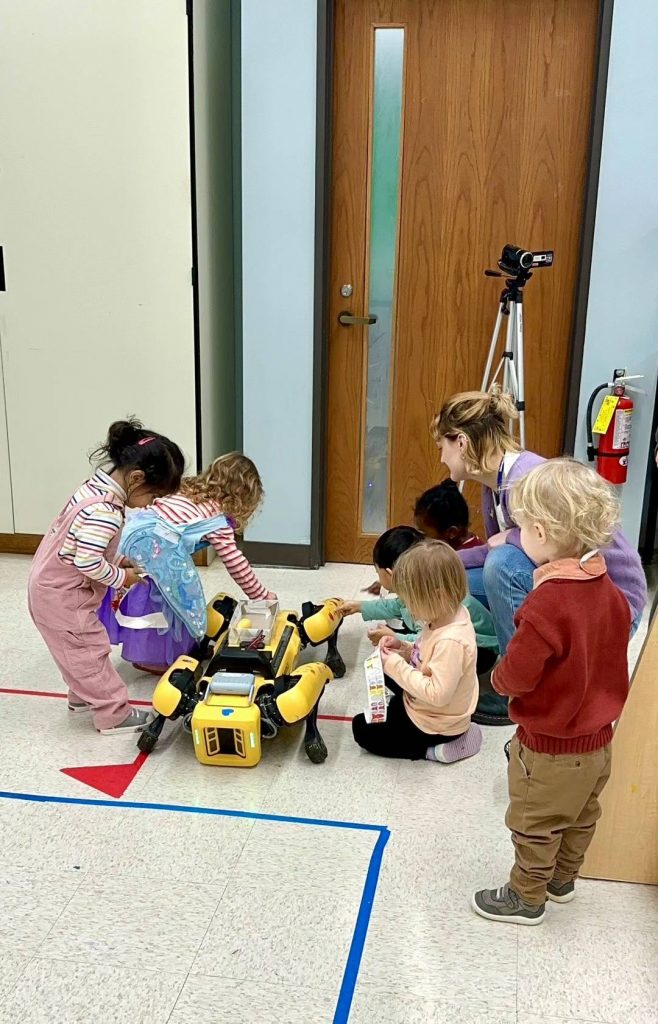 young students gathered around a robot