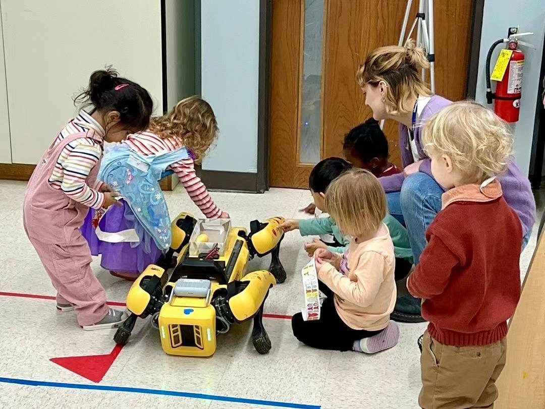 young students playing with a yellow robot