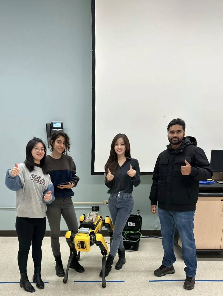 teachers standing around a robot, giving a thumbs' up gesture