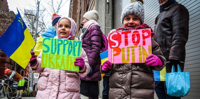 Children hold signs that say "Support Ukraine" and "Stop Putin."