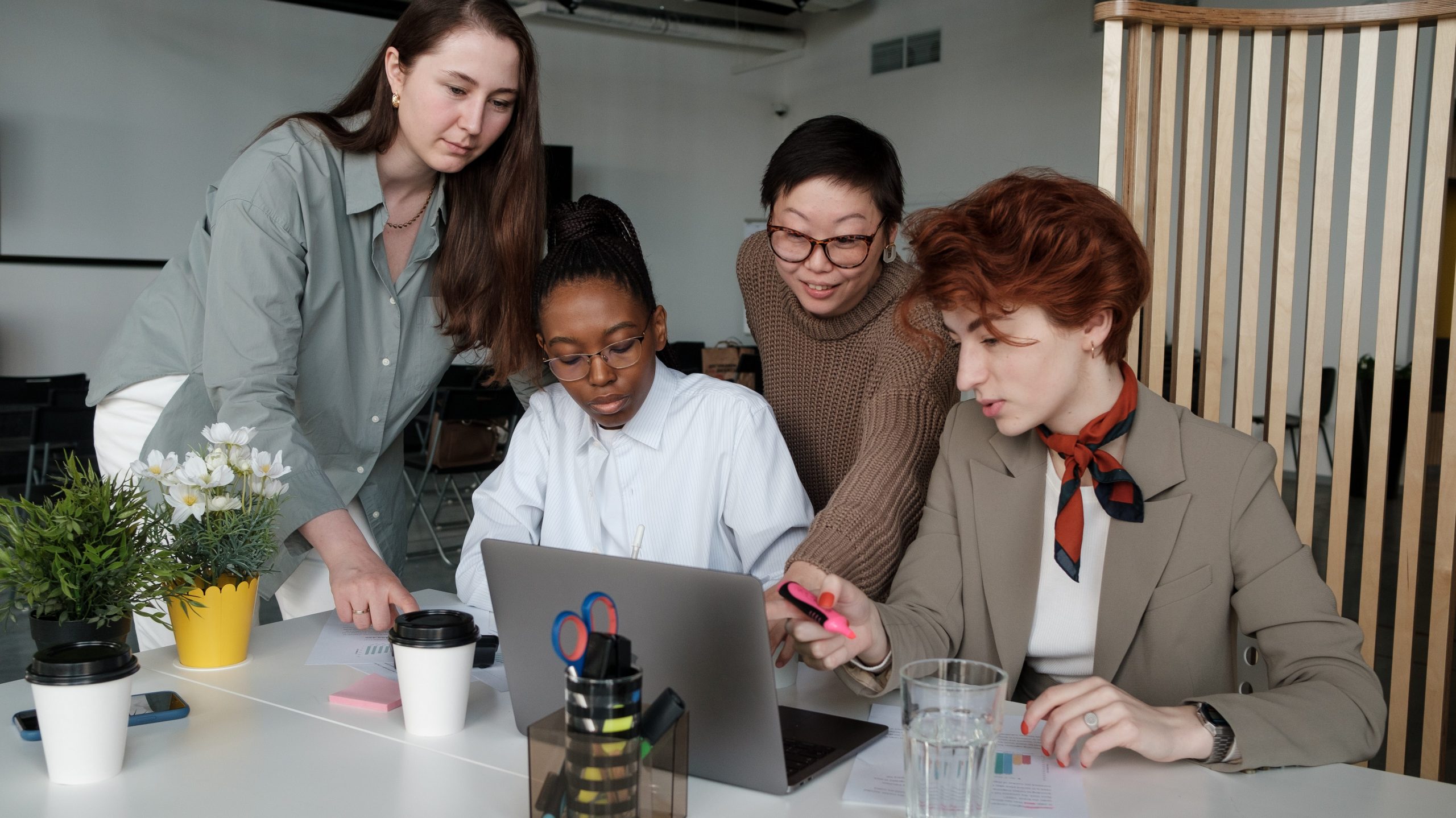 Four employees gathered around a computer to work.