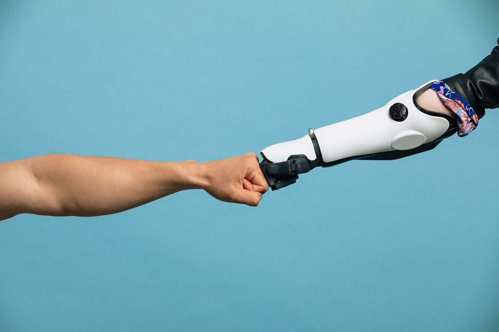 Human and robot arms doing a fist bump.