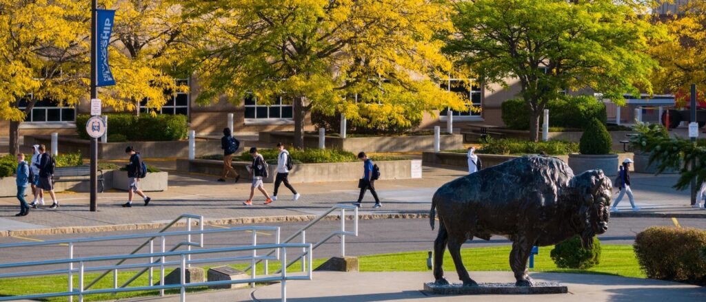 View of UB campus, with students walking and a buffalo statue