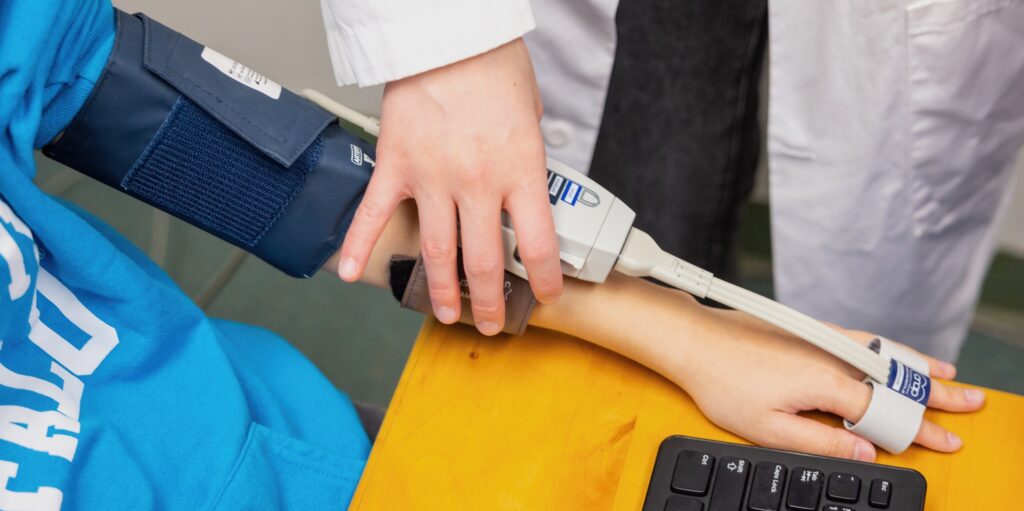 Undergraduate research assistant applying a blood pressure sensor to a participant